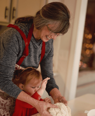 Grandmother kneading dough with granddaughter